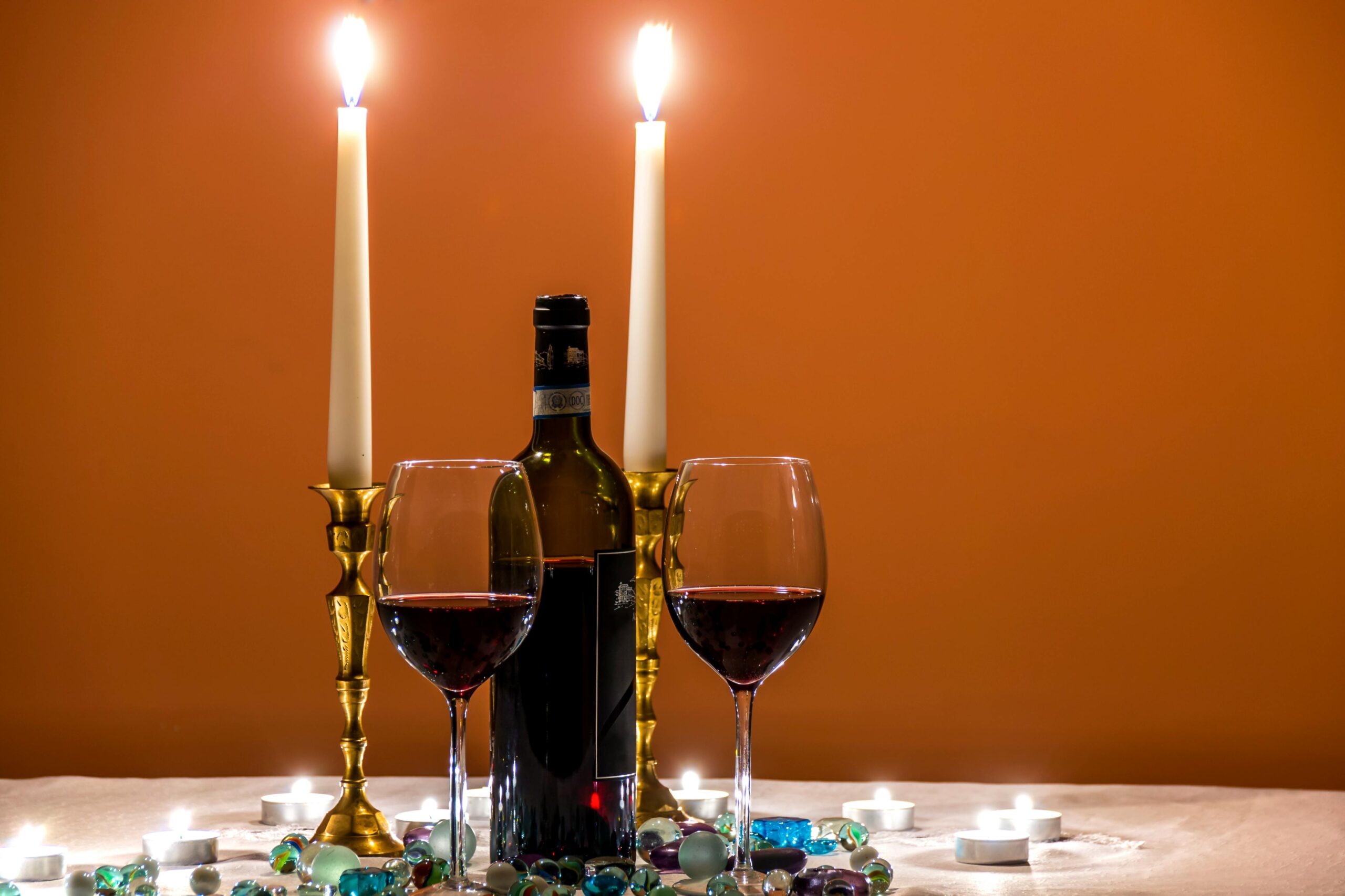 Cozy candlelit dinner setting with red wine and elegant glassware for a luxurious dining experience.